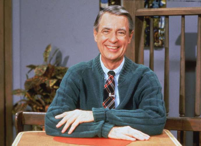 A picture of Mr Rogers wearing a green cardigan and smiling at the camera