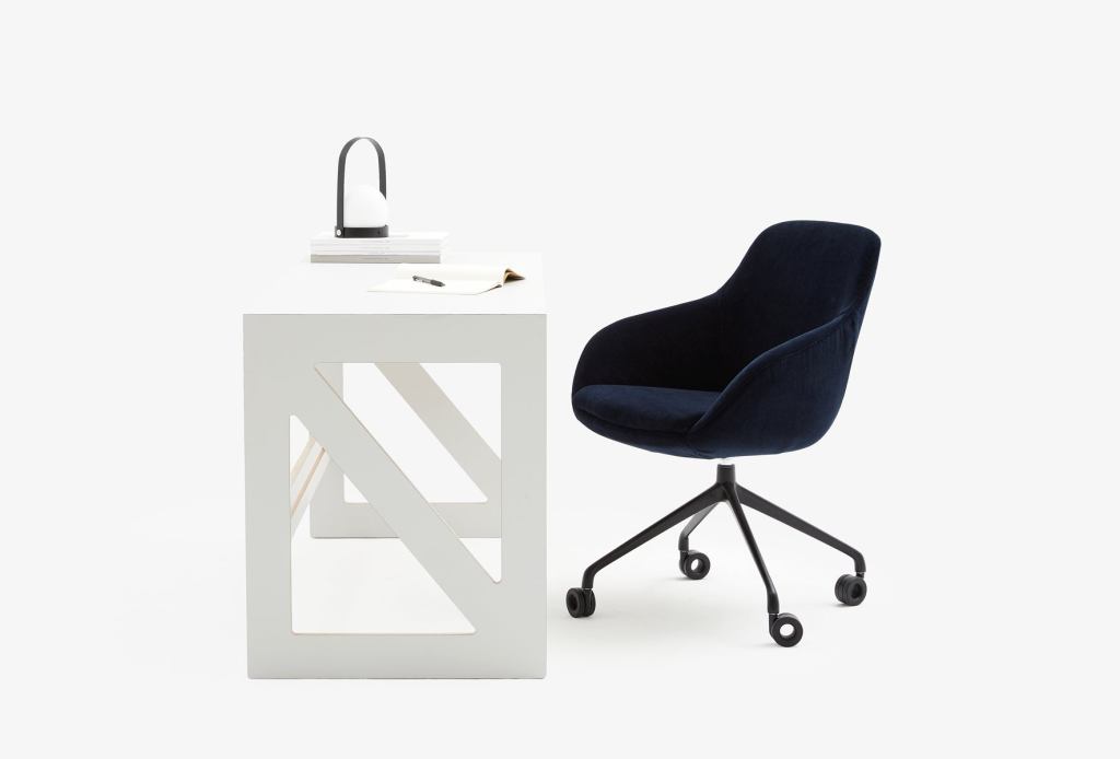 Otto Swivel Office Chair in navy blue velvet paired with a geometric white minimalist desk, creating a stylish and functional workspace.