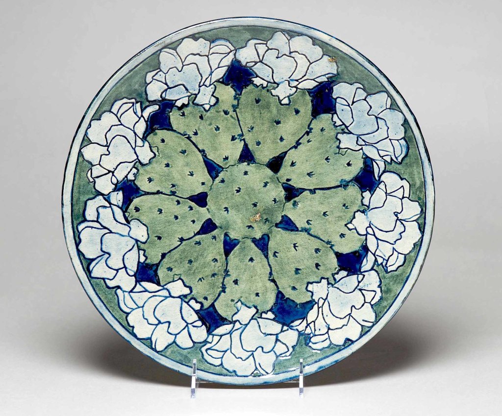 A plate with a border of flowering cactus, from about 1903, in an exhibition at Tulane.Credit...Owen Murphy