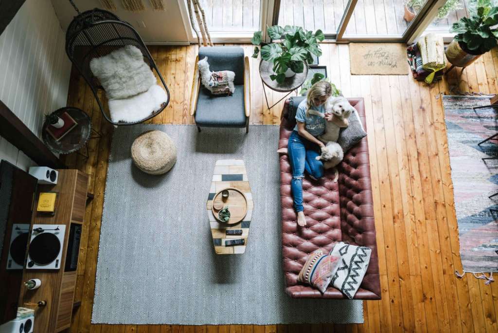 Top-down view of the Hunter Greenhouse living area with a burgundy tufted leather sofa, hanging chair, woven rug, and cozy decor.