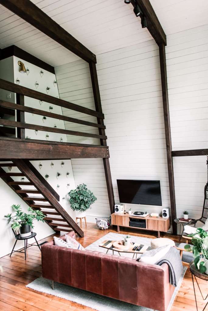 The Hunter Greenhouse living space with a burgundy leather sofa, wooden furniture, and large windows flooding the room with natural light.