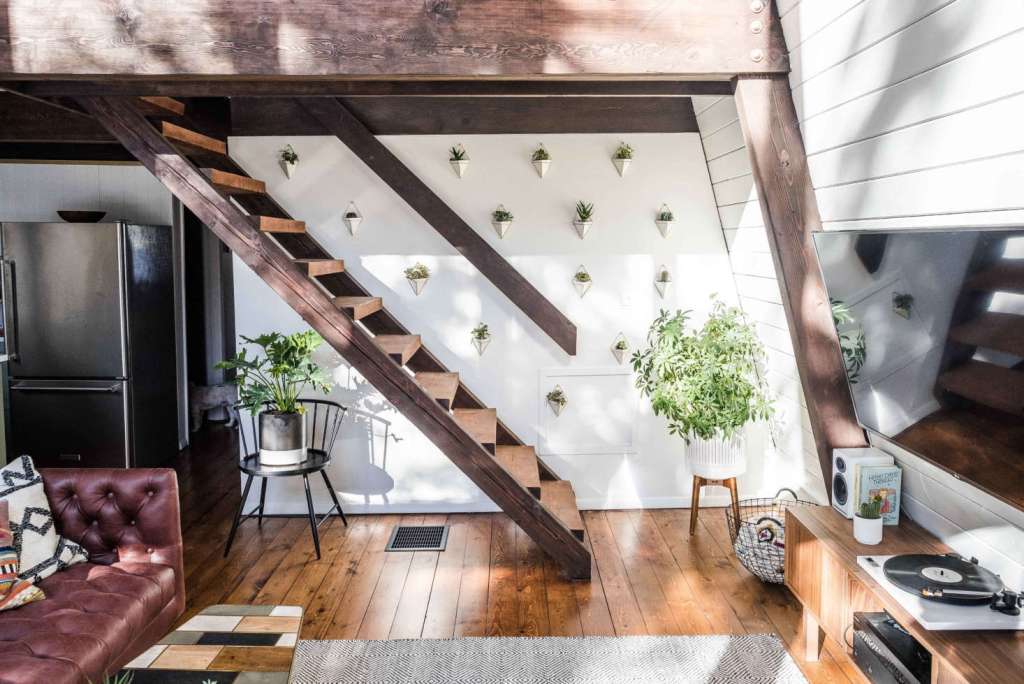 Rustic wooden staircase in the Hunter Greenhouse interior, decorated with potted plants and wall-mounted planters against white shiplap walls.