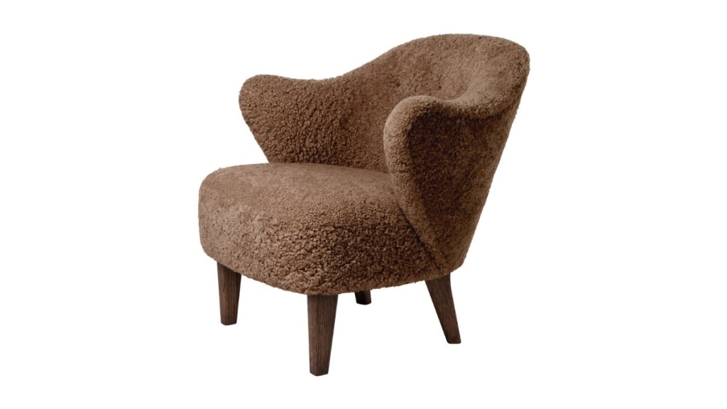 By Lassen lounge chair with a sculptural, organic form, upholstered in soft brown sheepskin, supported by wooden legs.
