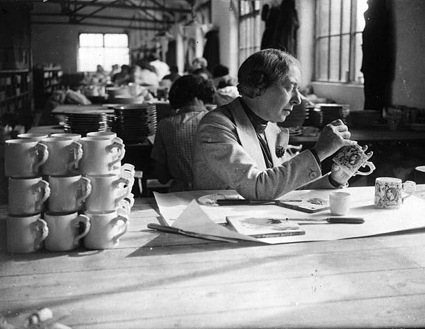 Dame Laura Knight painter of stage and circus life, putting the finishing touches to the Coronation mugs