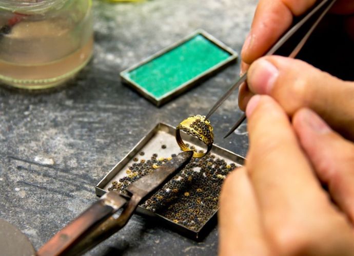 Metalsmith jeweller close-up image of hands working on a ring