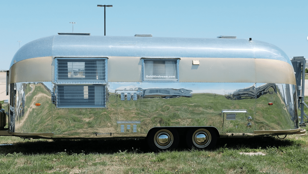 A polished 1962 Airstream travel trailer with a sleek aluminum exterior, reflecting Space Age design aesthetics and mid-century American innovation.