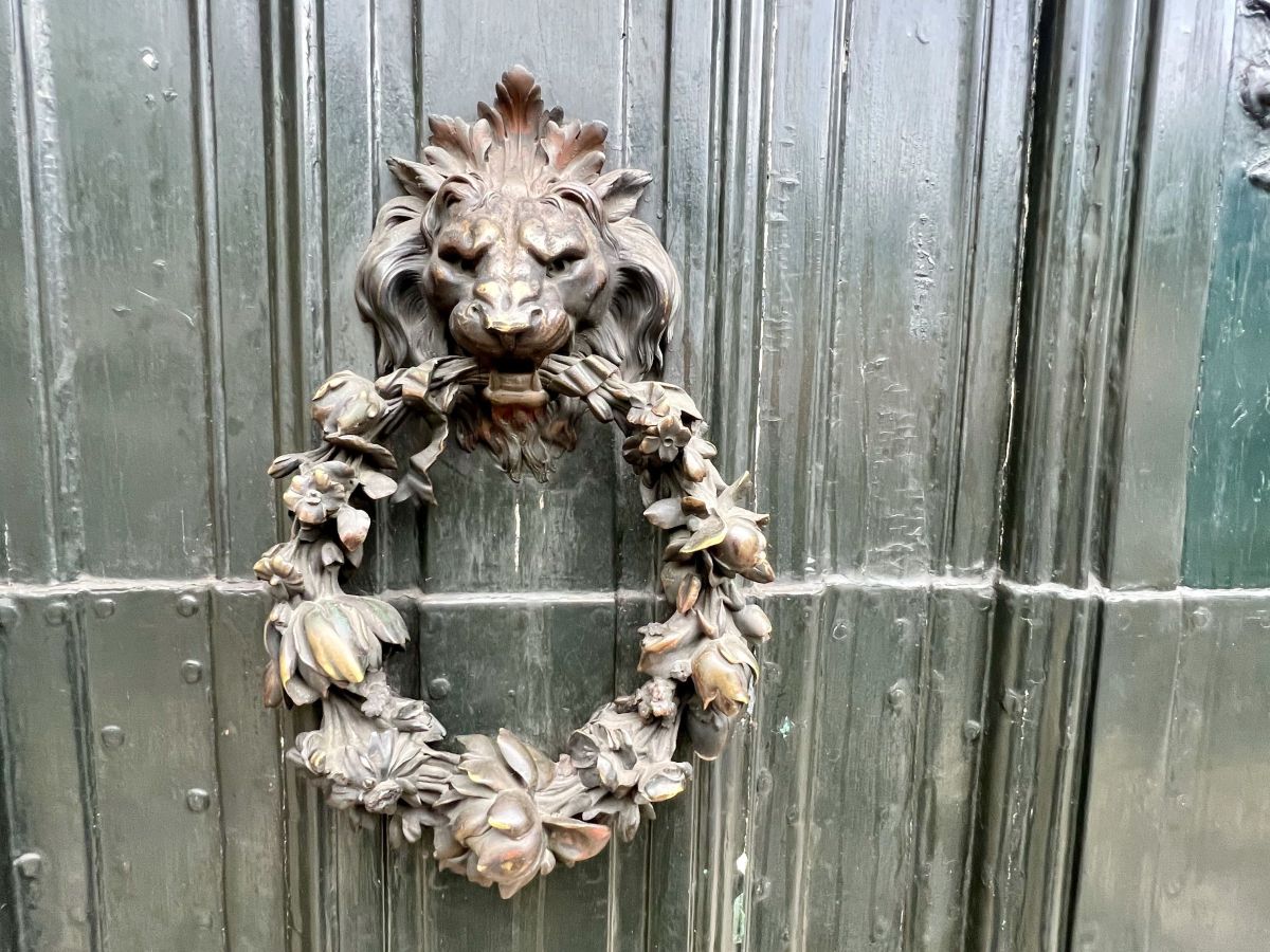 A Door Knocker in the shape of a Lion’s Head Holding a Wreath – Symbolism