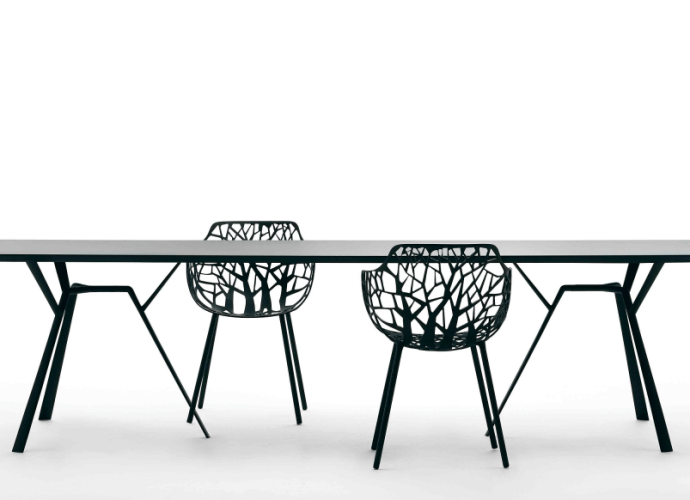 A modern dining set designed by Robby Cantarutti, featuring a sleek black table and intricate tree-branch-inspired chairs.