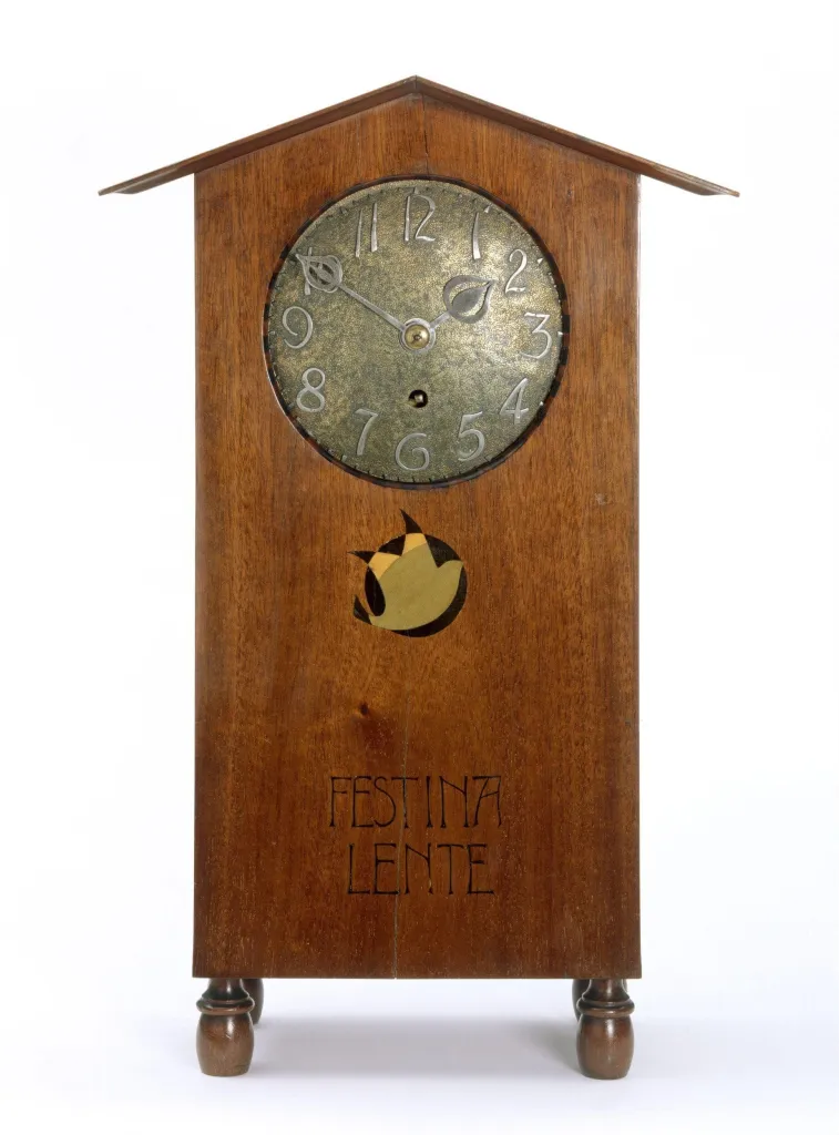 Mahogany case inlaid with coloured woods, the inlay including the inscription 'FESTINA LENTE'. The dial of copper Designed by Mackay Hugh Baillie Scott