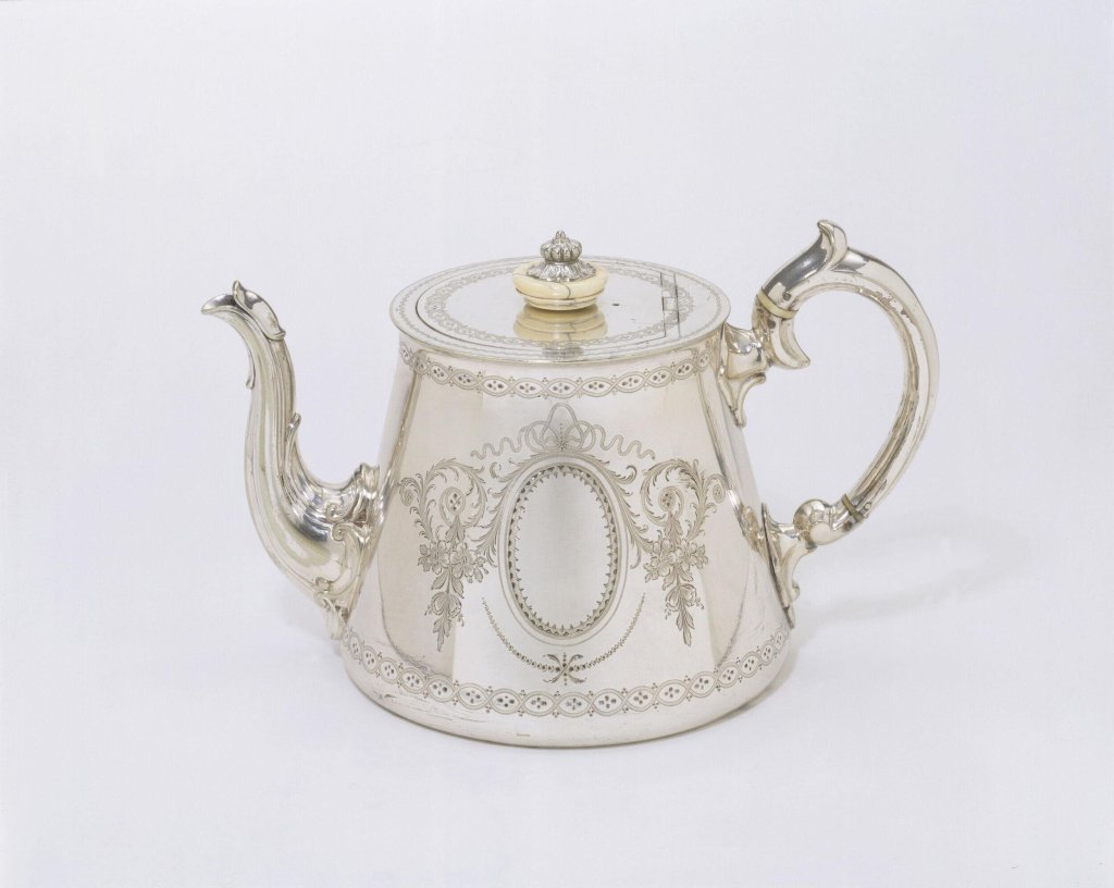 Electroplated nickel silver teapot with ivory additions, Birmingham, 1857, crafted by Elkington & Co., featuring intricate engraved designs and a decorative handle.


