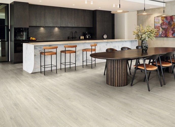 Open-plan kitchen and dining space featuring Karndean Korlok Pale Loire Oak (RKP8245) luxury vinyl flooring with dark cabinetry and timber furniture.