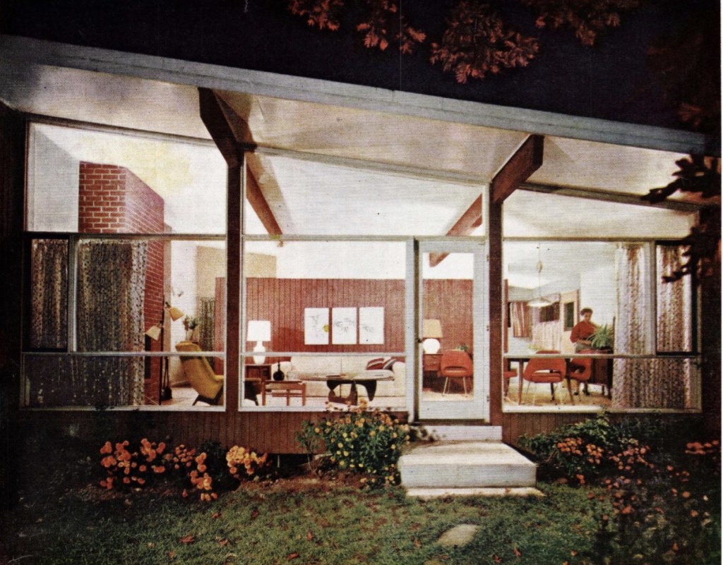 Nighttime view into illuminated living room through glass wall