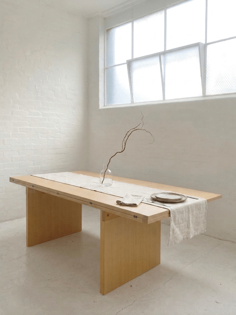 Piero De Martini La Barca ash dining table produced by Cassina in Italy in 1975, shown with plank top, panel supports, and minimalist table setting.